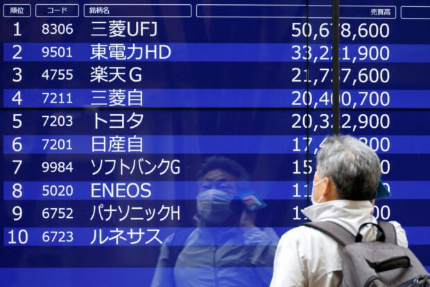 A man is reflected on an electric monitor displaying a stock quotation in Tokyo
